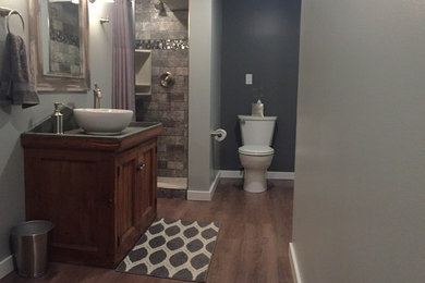 Inspiration for a gray tile brown floor bathroom remodel in Other with a one-piece toilet, gray walls, black countertops and a vessel sink