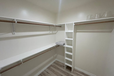 Example of a mid-sized minimalist gender-neutral vinyl floor and beige floor walk-in closet design in Houston