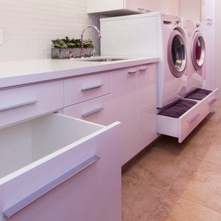 Large contemporary galley utility room in Los Angeles with a submerged sink, flat-panel cabinets, white cabinets, engineered stone countertops, pink walls, porcelain flooring and a side by side washer and dryer.