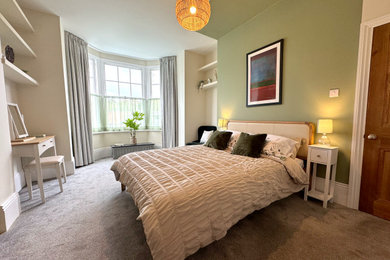 Large modern master bedroom in London with green walls and a feature wall.