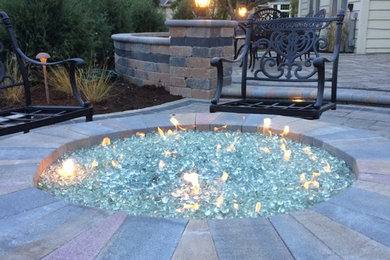 Example of a mid-sized transitional backyard stone patio design in Chicago with a fire pit and no cover