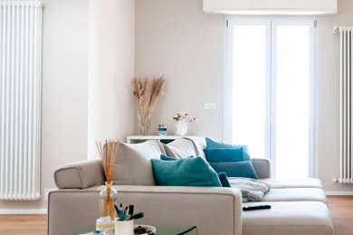 Immagine di un grande soggiorno moderno aperto con pareti beige, parquet chiaro, TV a parete e soffitto ribassato