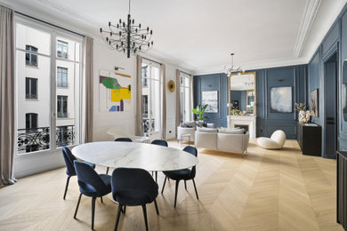 Réalisation d'une très grande salle à manger ouverte sur le salon design en bois avec un mur bleu, parquet clair, un manteau de cheminée en plâtre et un sol beige.