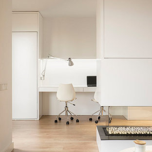 Inspiration for a small scandinavian study room in Barcelona with white walls, medium hardwood floors, a two-sided fireplace, a built-in desk and brown floor.