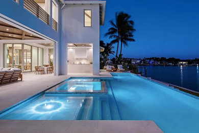 Hot tub - mid-sized coastal backyard rectangular and stone infinity hot tub idea in Miami