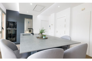 Imagen de cocina comedor nórdica grande con fregadero bajoencimera, salpicadero verde, electrodomésticos de acero inoxidable, una isla, suelo marrón y encimeras grises