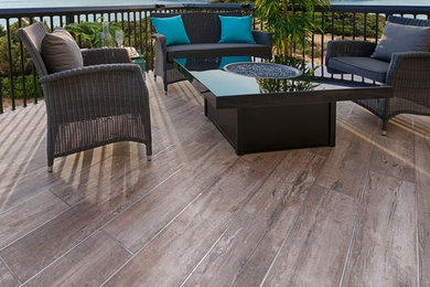 Example of a large island style backyard deck design in Calgary with no cover and a fire pit