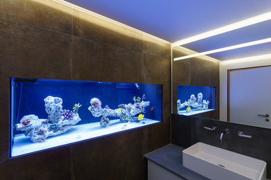 Moderne Gästetoilette mit flächenbündigen Schrankfronten, weißen Schränken, Wandtoilette mit Spülkasten, grauen Fliesen, weißer Wandfarbe, Keramikboden und Aufsatzwaschbecken in Sonstige