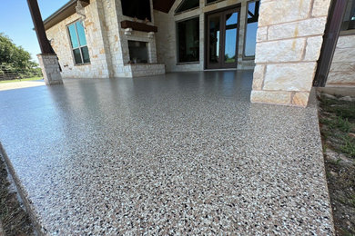 This is an example of a large concrete back porch design in Dallas with an awning.