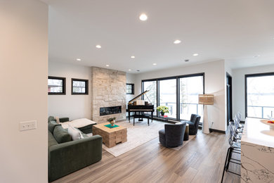 Inspiration for a mid-sized contemporary open concept laminate floor and brown floor living room remodel in Minneapolis with white walls, a standard fireplace, a stacked stone fireplace and no tv
