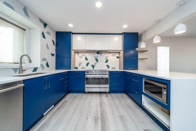 Inspiration for a contemporary vinyl floor and gray floor open concept kitchen remodel in Edmonton with a peninsula, a double-bowl sink, flat-panel cabinets, blue cabinets, quartzite countertops, green backsplash, stainless steel appliances and white countertops