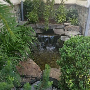 Photo of a small traditional backyard garden in New York with brick pavers and with waterfall.