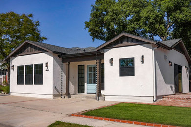 Large transitional white one-story stucco exterior home photo in Los Angeles with a shingle roof and a black roof