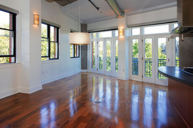 Modelo de sala de estar tipo loft moderna grande con suelo de madera en tonos medios y vigas vistas