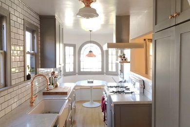 Inspiration for a small country u-shaped light wood floor and beige floor eat-in kitchen remodel in Los Angeles with a farmhouse sink, shaker cabinets, gray cabinets, marble countertops, white backsplash, subway tile backsplash, stainless steel appliances and no island