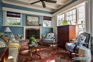 Example of a mid-sized country open concept medium tone wood floor living room design in Charleston with blue walls, a standard fireplace, a brick fireplace and a concealed tv