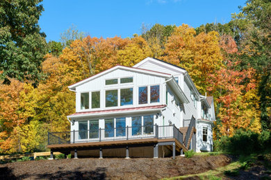 Imagen de fachada de casa blanca y roja clásica renovada de tres plantas con revestimiento de aglomerado de cemento, tejado a dos aguas, tejado de metal y panel y listón