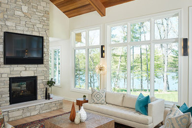 Inspiration for a large 1950s open concept light wood floor and brown floor living room remodel in Grand Rapids with white walls, a standard fireplace, a stone fireplace and a wall-mounted tv