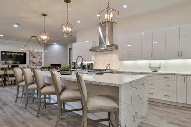 Inspiration for a large modern vinyl floor and beige floor eat-in kitchen remodel in San Diego with a drop-in sink, flat-panel cabinets, white cabinets, quartzite countertops, white backsplash, subway tile backsplash, stainless steel appliances, an island and white countertops
