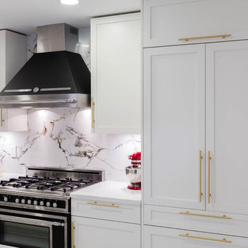 A kitchen with white shaker cabinets and Gold / Brass hardware