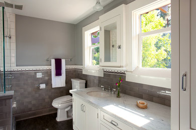 Mid-sized arts and crafts master gray tile and subway tile corner shower photo in Los Angeles with recessed-panel cabinets, white cabinets, a one-piece toilet, gray walls, an undermount sink and marble countertops