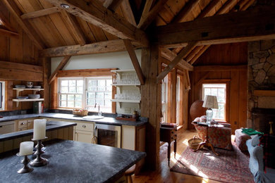 Example of a mid-sized mountain style l-shaped medium tone wood floor eat-in kitchen design in Burlington with a drop-in sink, shaker cabinets, white cabinets, soapstone countertops, gray backsplash and an island