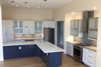 Inspiration for a mid-sized contemporary galley light wood floor enclosed kitchen remodel in Baltimore with an undermount sink, shaker cabinets, white cabinets, quartz countertops, gray backsplash, glass tile backsplash, stainless steel appliances and an island