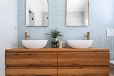 Inspiration for a bathroom in Sydney with medium wood cabinets, gray tile, wood benchtops, a double vanity and a floating vanity.
