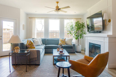 Inspiration for a transitional open concept medium tone wood floor and brown floor living room remodel in Dallas with white walls, a standard fireplace and a wall-mounted tv