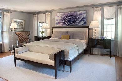 This is an example of a large transitional master bedroom in Philadelphia with grey walls, medium hardwood floors, a standard fireplace, a tile fireplace surround and brown floor.