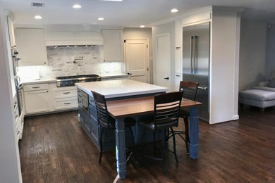 Eat-in kitchen - mid-sized transitional l-shaped dark wood floor and brown floor eat-in kitchen idea in Dallas with shaker cabinets, white cabinets, quartz countertops, white backsplash, marble backsplash, stainless steel appliances, an island, white countertops and a farmhouse sink