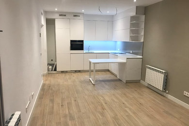 Ejemplo de cocinas en L moderna de tamaño medio abierta con fregadero bajoencimera, armarios con paneles lisos, puertas de armario blancas, encimera de cuarzo compacto, salpicadero verde, electrodomésticos con paneles, suelo de baldosas de cerámica, península, suelo beige y encimeras blancas