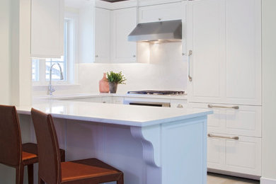 Open concept kitchen - small transitional u-shaped light wood floor open concept kitchen idea in Boston with an undermount sink, recessed-panel cabinets, white cabinets, quartz countertops, white backsplash, stone slab backsplash, paneled appliances and a peninsula