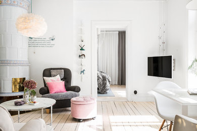 This is an example of a scandinavian living room in Malmo with white walls, light hardwood floors, a wall-mounted tv and beige floor.
