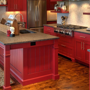 Idée de décoration pour une arrière-cuisine tradition en U de taille moyenne avec un évier encastré, un placard avec porte à panneau encastré, des portes de placard rouges, un plan de travail en granite, une crédence blanche, une crédence en mosaïque, un électroménager en acier inoxydable, un sol en bois brun et un îlot central.