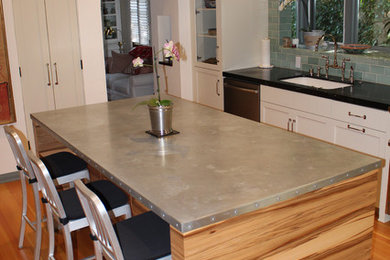 Mid-sized trendy l-shaped light wood floor enclosed kitchen photo in Los Angeles with an undermount sink, recessed-panel cabinets, white cabinets, green backsplash, ceramic backsplash and stainless steel appliances