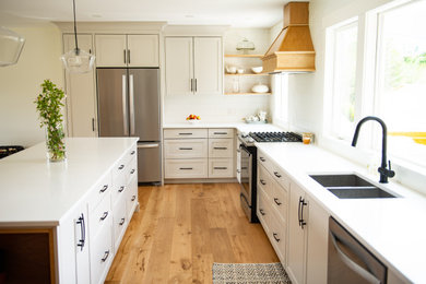 Example of a huge arts and crafts l-shaped light wood floor and brown floor eat-in kitchen design in Vancouver with an undermount sink, shaker cabinets, white cabinets, quartzite countertops, white backsplash, porcelain backsplash, stainless steel appliances, an island and white countertops