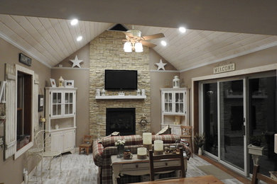 Inspiration for a mid-sized country open concept living room in Baltimore with beige walls, light hardwood floors, a standard fireplace, a stone fireplace surround and a wall-mounted tv.