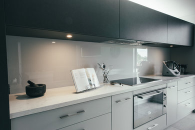 This is an example of a mid-sized contemporary galley kitchen pantry in Perth with an undermount sink, grey cabinets, quartz benchtops, grey splashback, glass sheet splashback, stainless steel appliances, ceramic floors and with island.