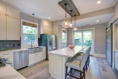 Inspiration for a mid-sized contemporary l-shaped light wood floor and gray floor enclosed kitchen remodel in San Francisco with a farmhouse sink, raised-panel cabinets, white cabinets, quartzite countertops, multicolored backsplash, cement tile backsplash, stainless steel appliances and an island