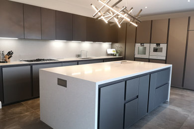 This is an example of a large contemporary l-shaped open plan kitchen in London with glass-front cabinets, brown cabinets, quartz worktops, an island, a built-in sink, integrated appliances, porcelain flooring and brown floors.