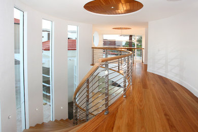 Photo of a mediterranean wood curved staircase in Gold Coast - Tweed with open risers and mixed railing.