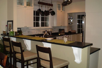 Open concept kitchen - mid-sized l-shaped open concept kitchen idea in Milwaukee with recessed-panel cabinets, white cabinets, gray backsplash, stone tile backsplash and stainless steel appliances