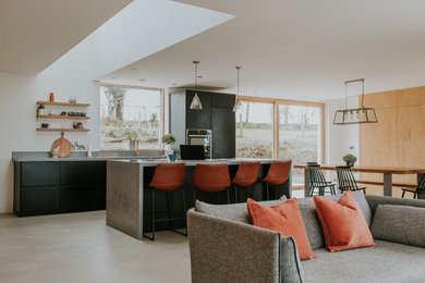 Design ideas for a medium sized contemporary galley open plan kitchen in Other with flat-panel cabinets, black cabinets, concrete worktops, grey splashback, an island, grey floors and grey worktops.