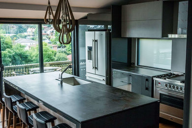 Mid-sized modern l-shaped open plan kitchen in Other with flat-panel cabinets, black cabinets and with island.