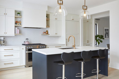 Example of a mid-sized farmhouse galley light wood floor and yellow floor open concept kitchen design in Toronto with an undermount sink, shaker cabinets, yellow cabinets, quartz countertops, white backsplash, porcelain backsplash, paneled appliances, an island and white countertops