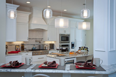 This is an example of a large transitional u-shaped open plan kitchen in Raleigh with a single-bowl sink, recessed-panel cabinets, white cabinets, granite benchtops, beige splashback, stainless steel appliances, medium hardwood floors and with island.