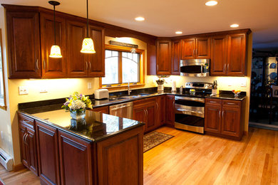 Inspiration for a mid-sized traditional u-shaped eat-in kitchen in Boston with a double-bowl sink, recessed-panel cabinets, dark wood cabinets, granite benchtops, stainless steel appliances, medium hardwood floors and no island.