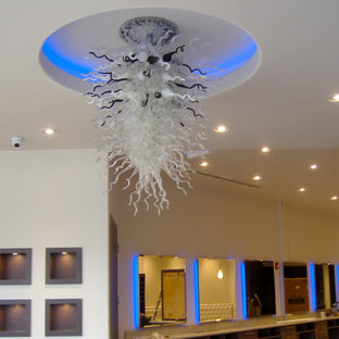 Inspiration pour une grande salle de cinéma design ouverte avec un mur blanc, un sol en travertin et un téléviseur encastré.