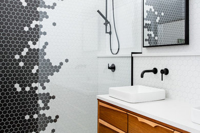 Example of a mid-century modern 3/4 black tile, black and white tile, multicolored tile, white tile and mosaic tile white floor bathroom design in Calgary with medium tone wood cabinets, white walls, a vessel sink, white countertops and flat-panel cabinets